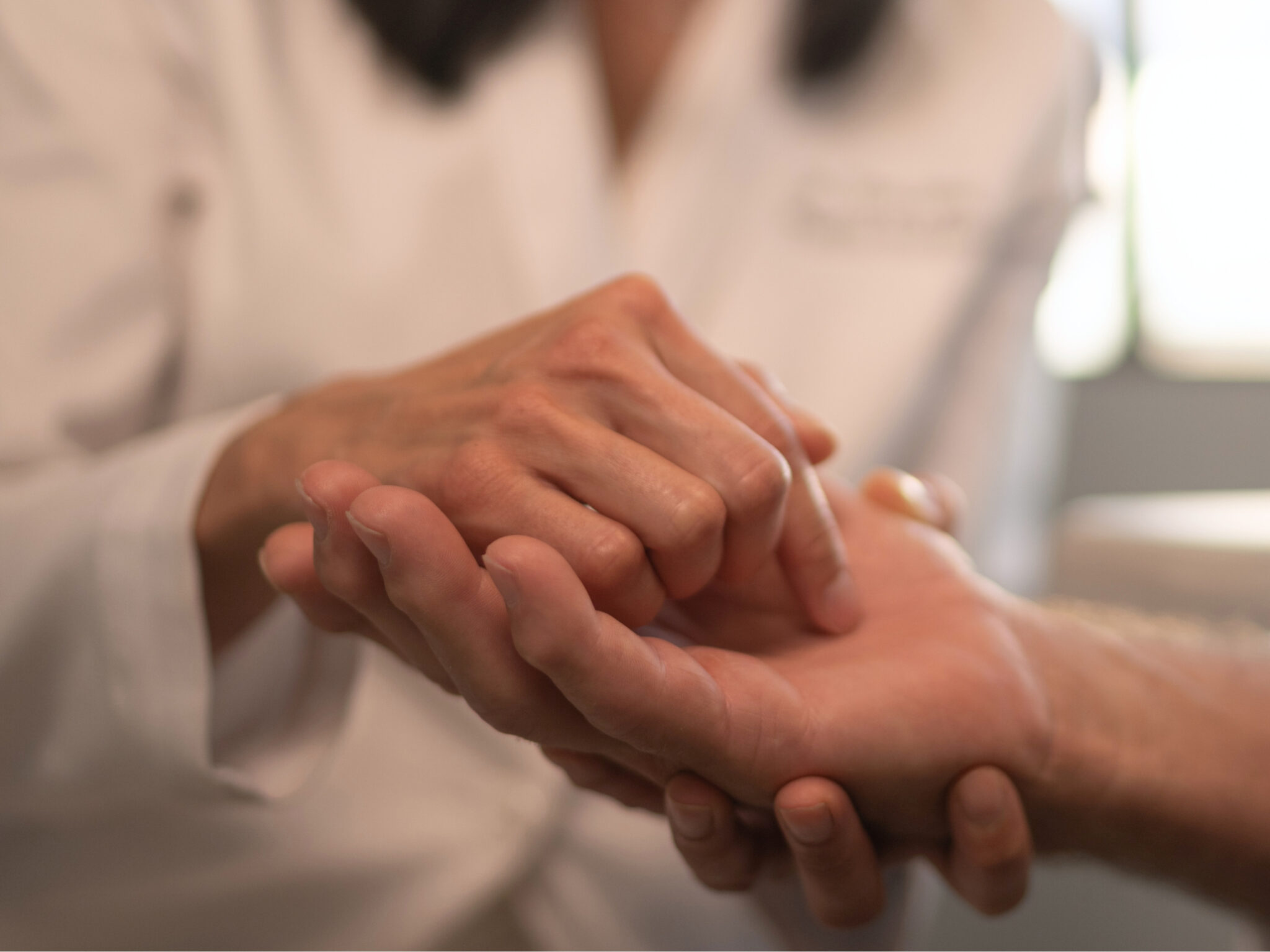 Dr. Tina Jenq gently holding a patient's hand during an exam